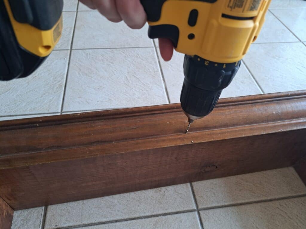 Drilling a pilot hole into a wooden frame to attach to vertical herb garden box.