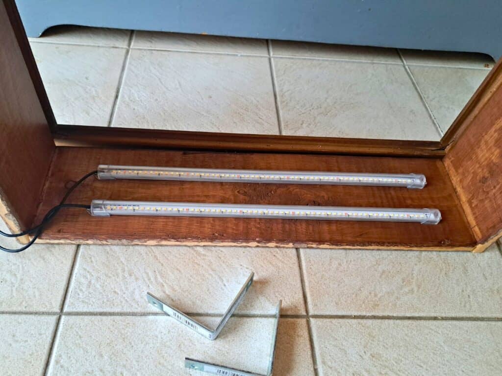 Herb grow lights being mounted to kitchen wall herb garden planter box.