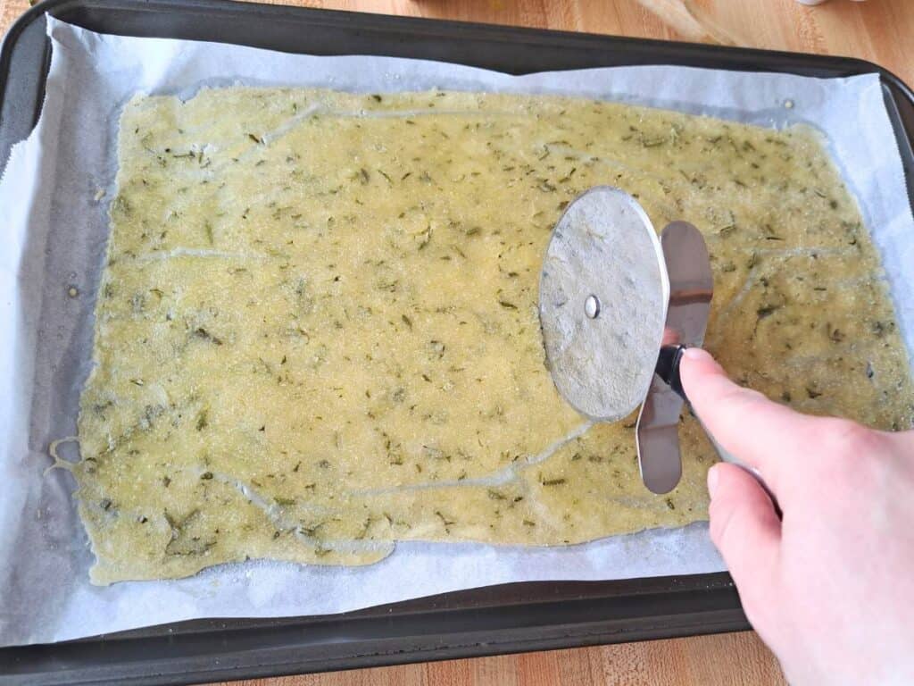 Scoring the sourdough discard crackers with a pizza cutter.