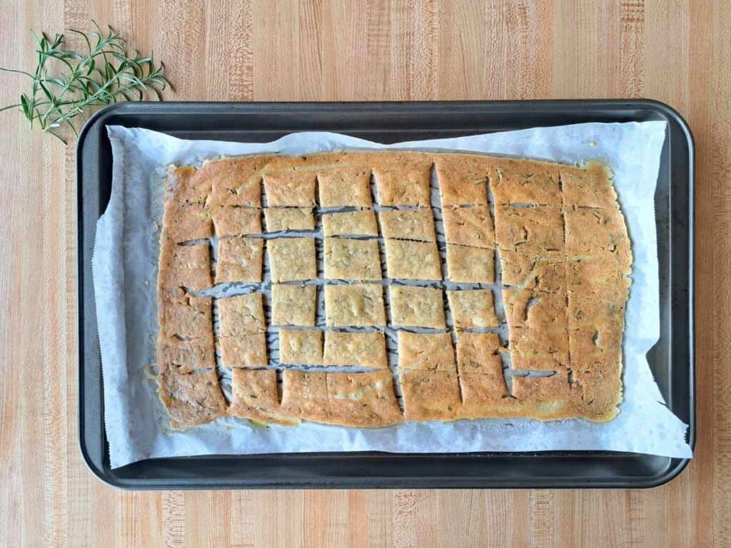 Letting the sourdough discard crackers with rosemary cool on the baking sheet after baking.