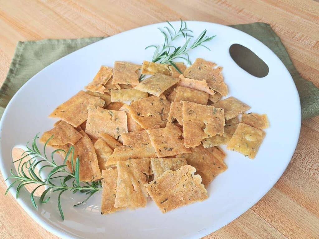 Rosemary olive oil discard crackers laid out on a white serving plate.