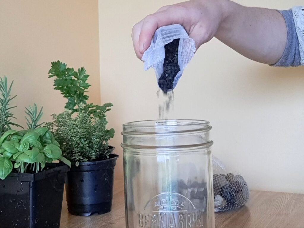 Adding activated charcoal to the bottom of the mason jar.