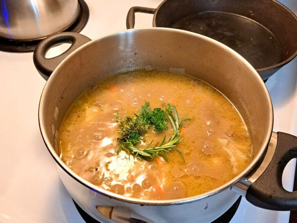 An herbal soup wreath simmering in a pot of beef stew on the stove.