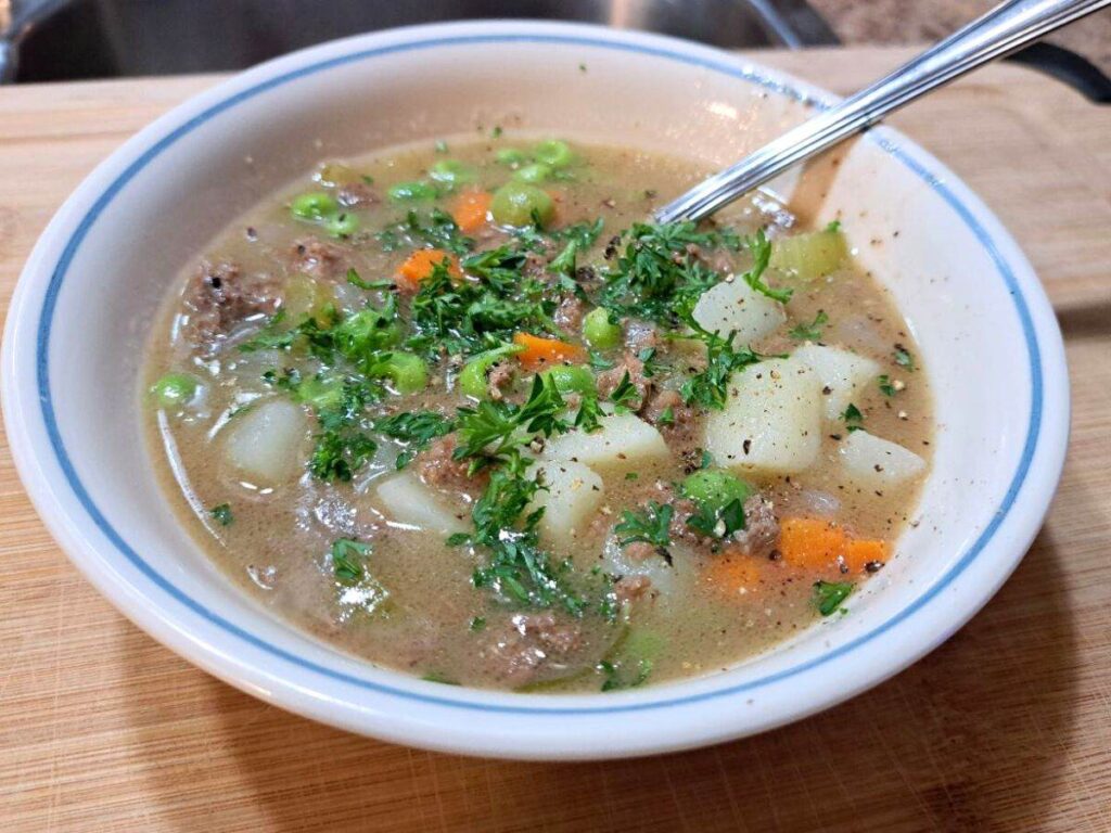 A bowl of beef stew with fresh parsley on top.