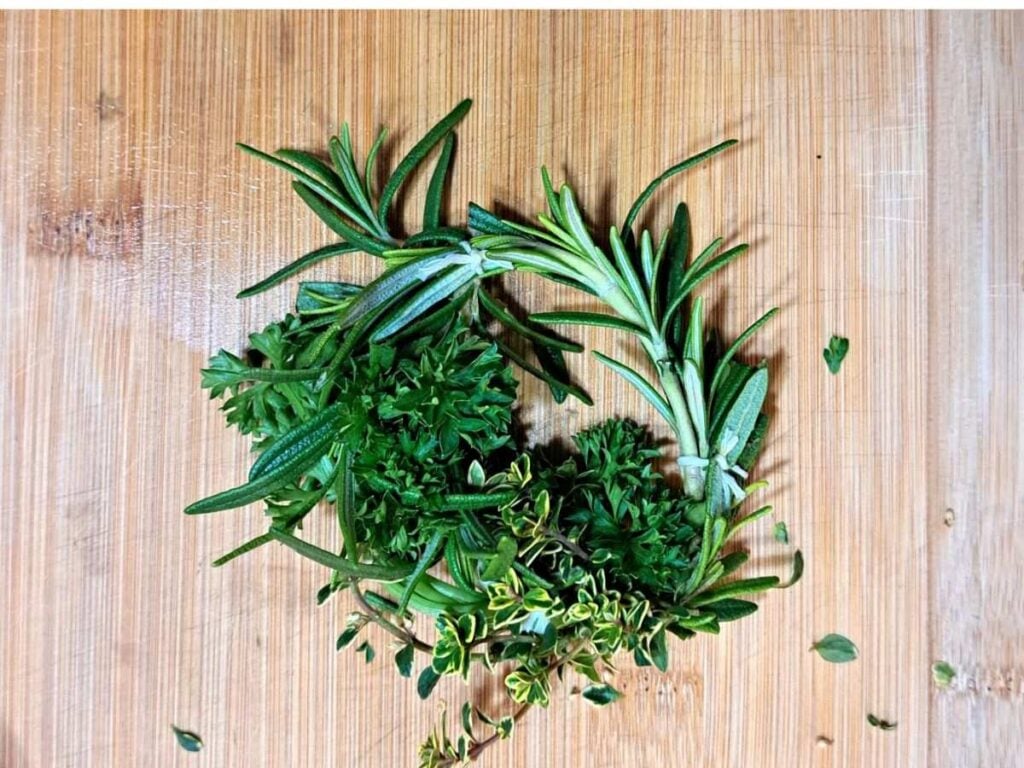 A close up of an herbal soup wreath sitting on a wooden cutting board.