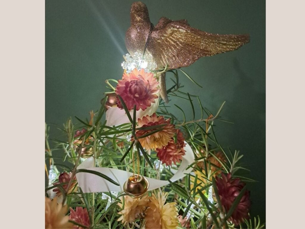 Close up of a dove tree topper on a small rosemary Christmas tree.