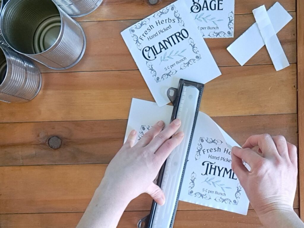 Overhead shot of someone ripping paper tin can herb labels with a ruler.