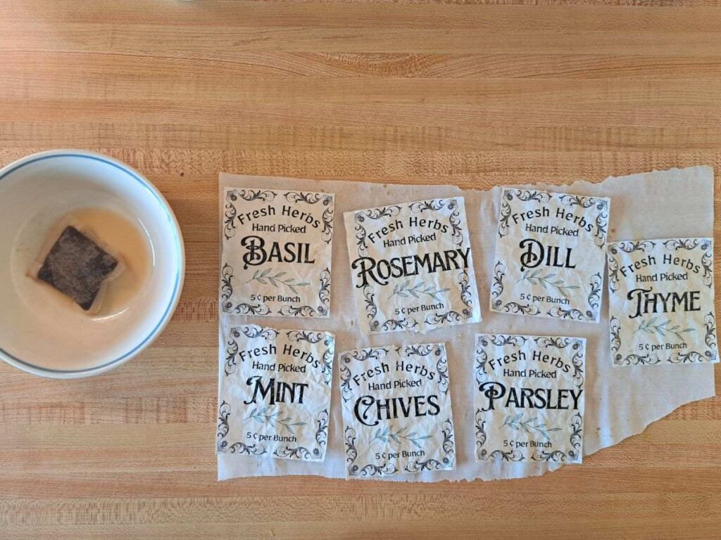 A tea bag sitting in a small bowl next to seven paper herb labels.