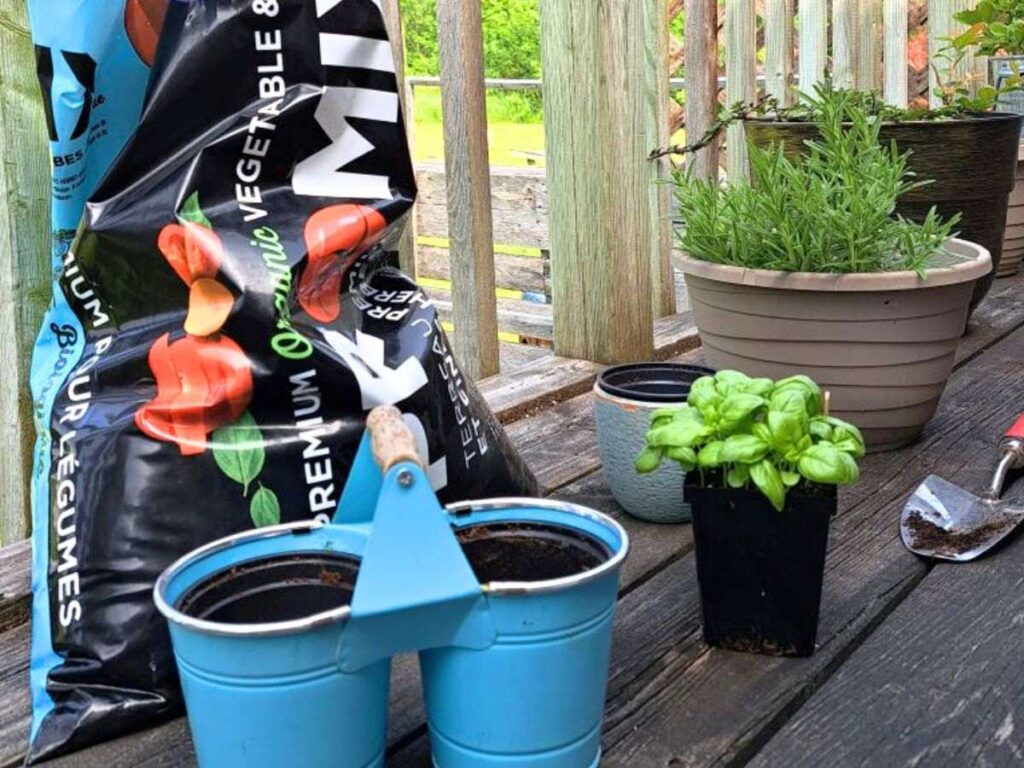 Potting mix, small pots, herbs and a shovel sitting out on the deck ready for planting.