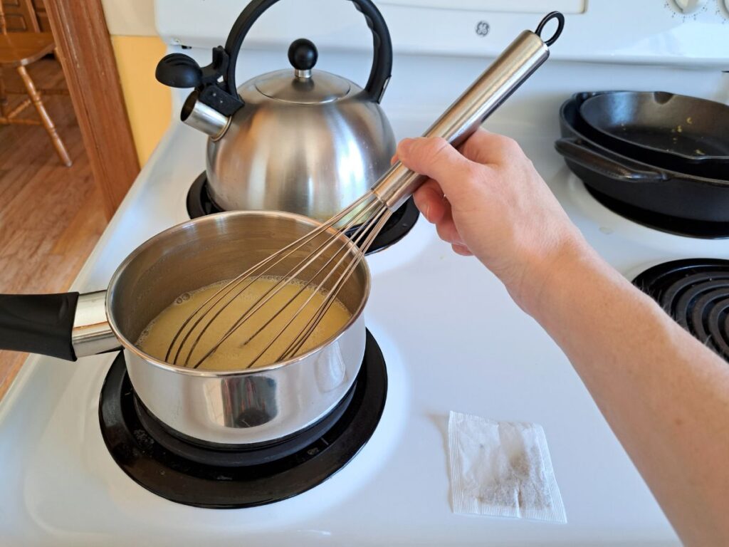 Heating milk, honey, and butter in a saucepan on the stove to infuse the chamomile.