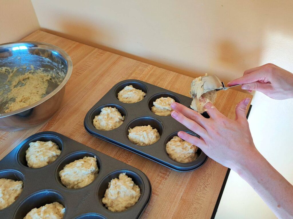 Spooning the chamomile and honey muffin batter into the muffin tins.