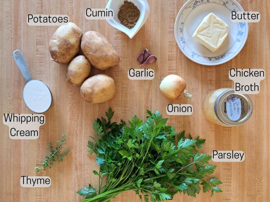 Ingredients laid out on a wooden counter to make potato and parsley soup.