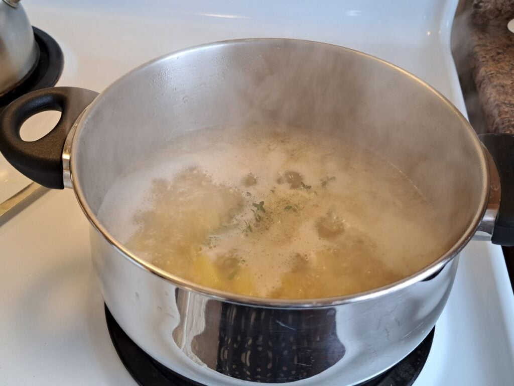 Parsley soup simmering on the stove in a large metal pot.
