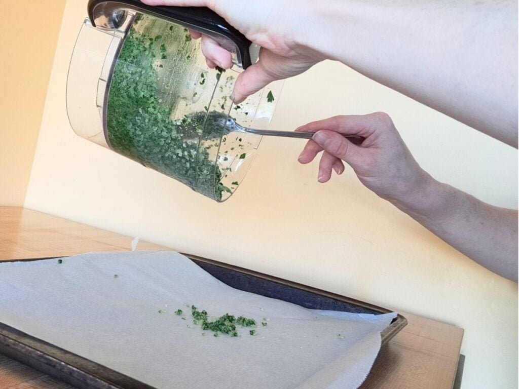 Adding the garlic parsley salt mixture to a parchment lined baking sheet.