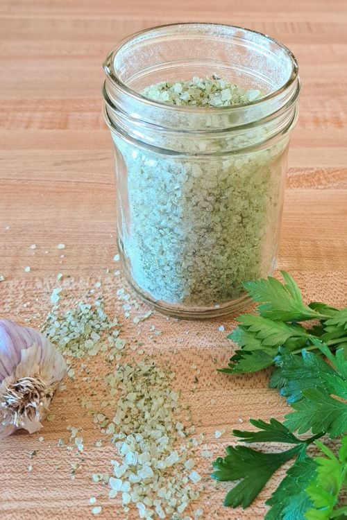 Finishing salt with parsley and garlic on the counter in a mason jar.