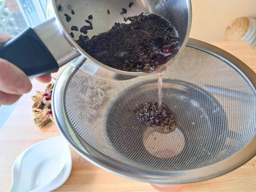 Straining out the lavender honey syrup through a fine mesh sieve.
