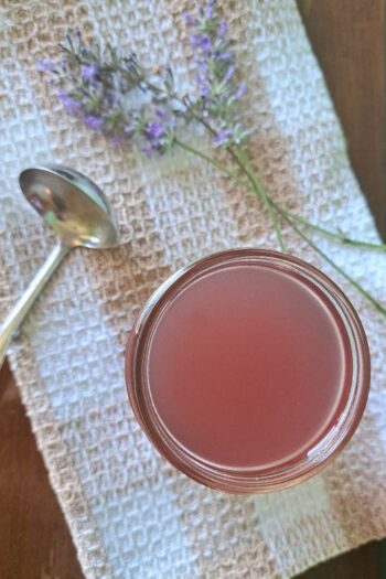 An overhead view of the lavender simple syrup in a clear glass canning jar.