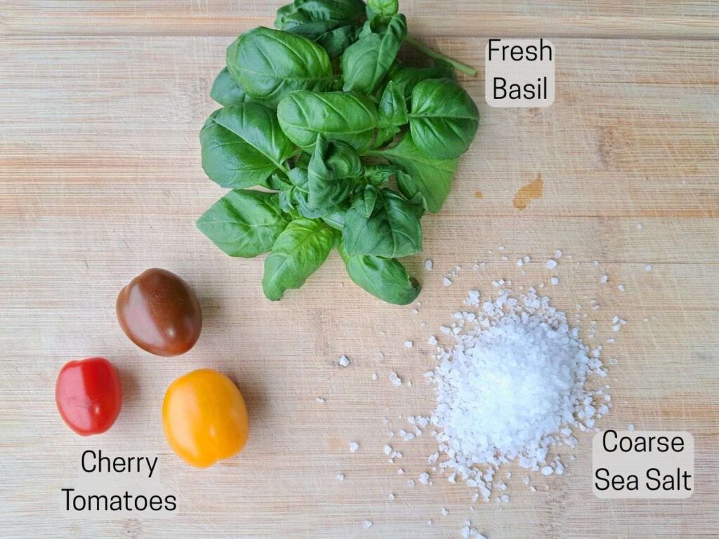 Ingredients laid out on a cutting board. There are tomatoes, basil, and salt.