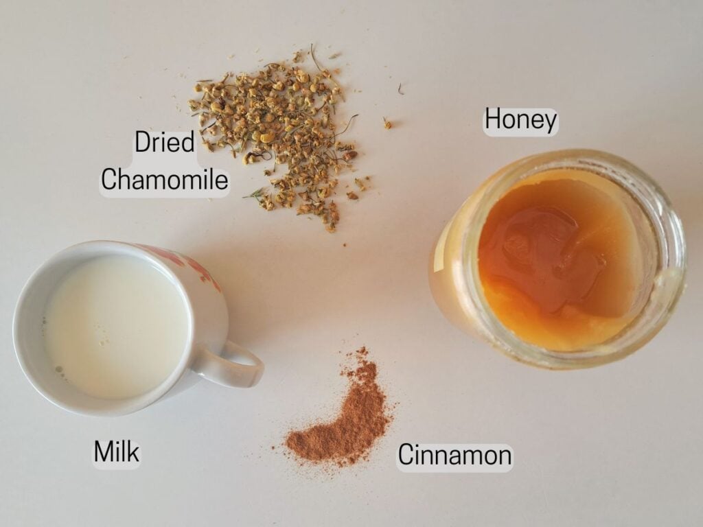Ingredients gathered to make a chamomile moon milk recipe. There is chamomile, milk, honey, and cinnamon.