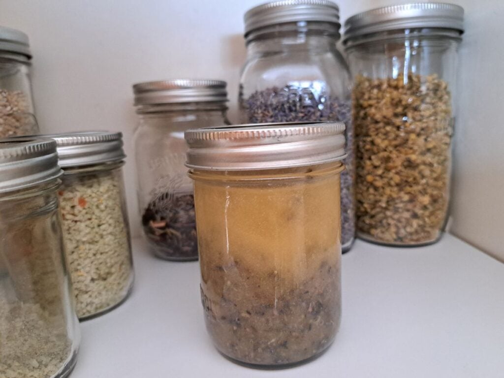 Lavender infused honey sitting in the pantry in a jar with other dried herbs.