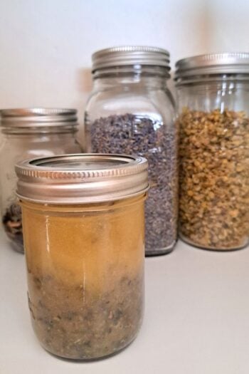 A close up of herb infused honey sitting on a pantry shelf.