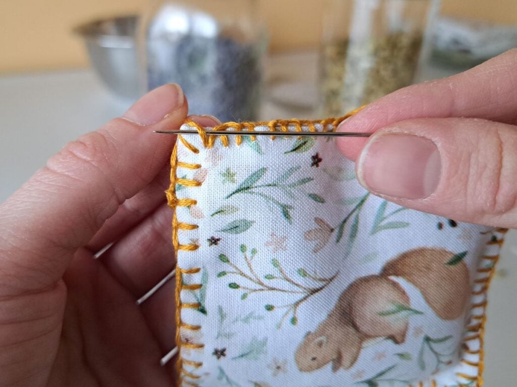 Creating a knot at the top edge, to secure stitching.