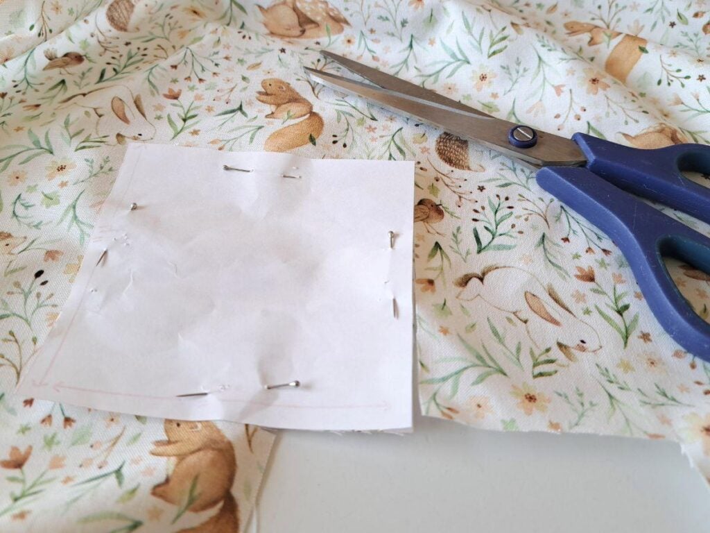 Attaching paper template to fabric with pins so the fabric can be cut out.