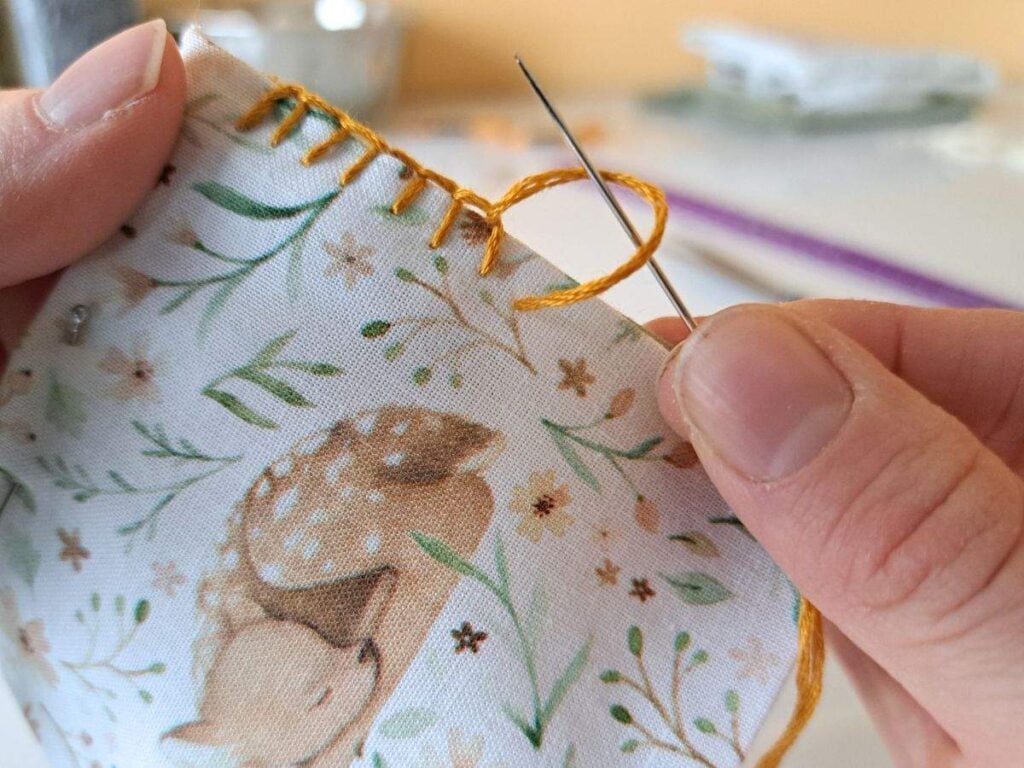 Looping needle through thread to create a blanket stitch.