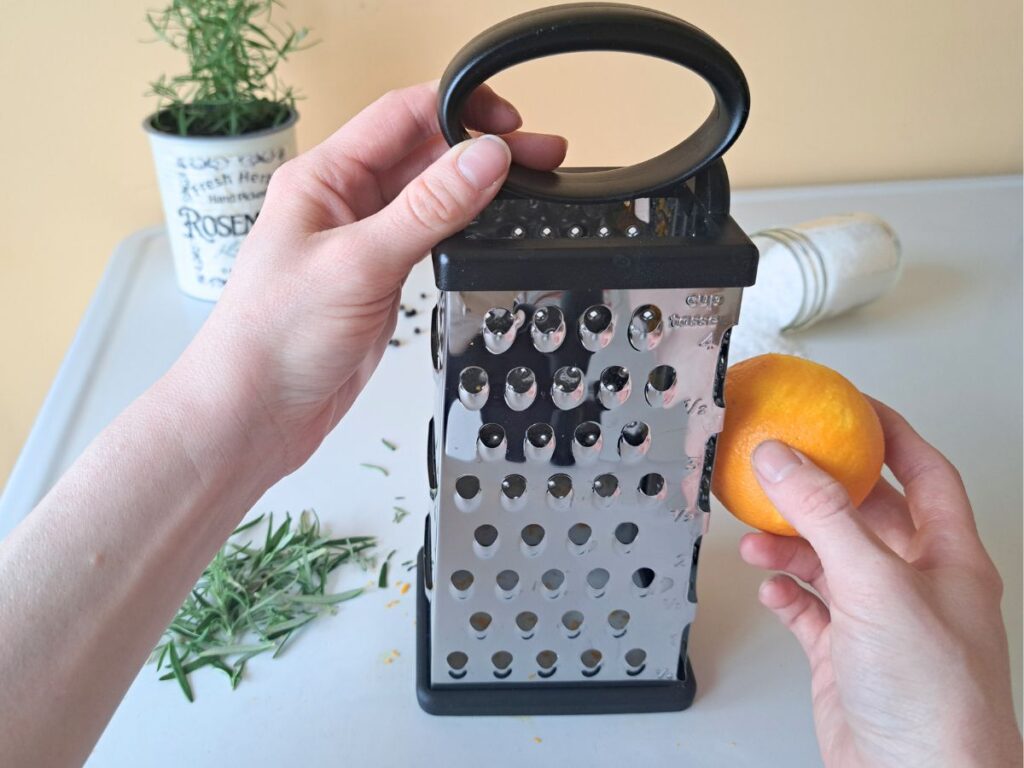 Grating the zest of one orange using a cheese grater.