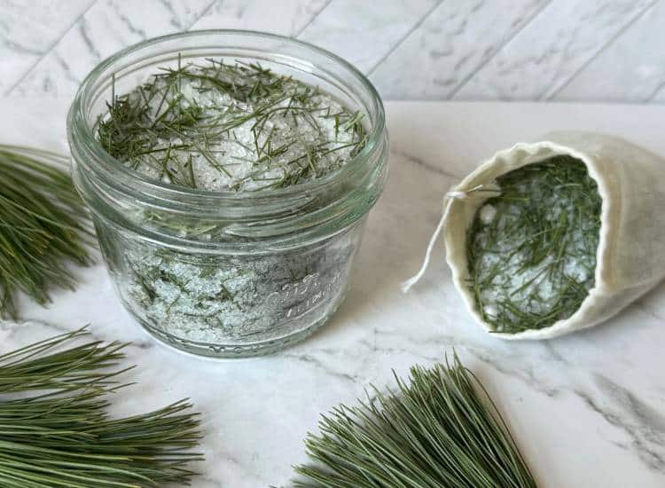 A small glass jar and bag with pine bath salts inside.