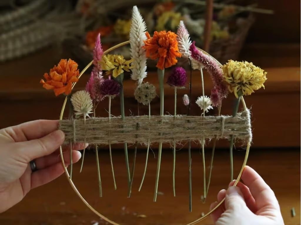 Hands holding up a small dried flower wreath.